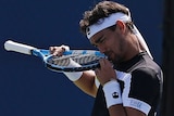 Fabio Fognini bites part of his racquet in frustration after losing a point.