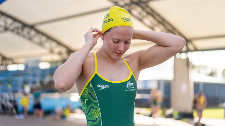 A young female swimmer wearing Australian togs and a yellow swimming cap