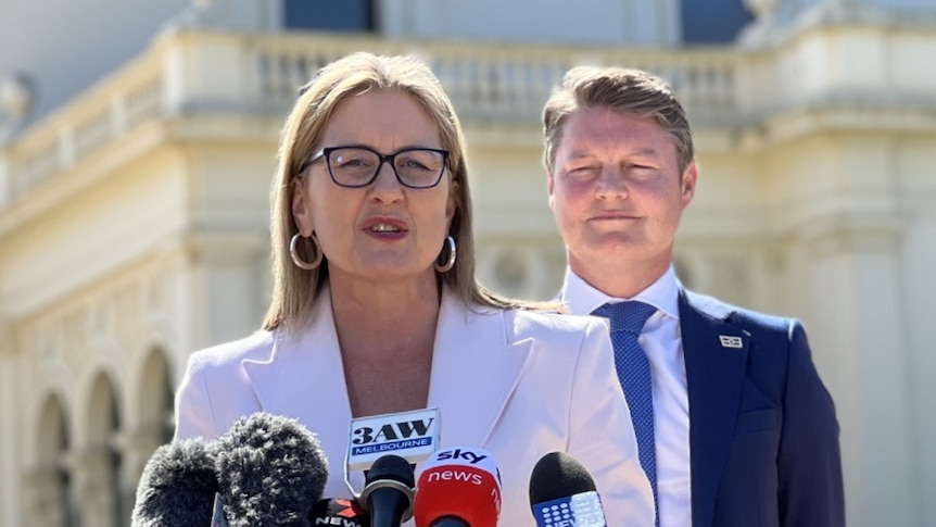 Victorian Premier Jacinta Allan addressing media outside a white building with Deputy Ben Carrol standing behind her 