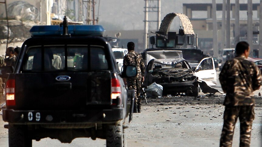 Afghan security force members inspect the site of the suicide car bombing.
