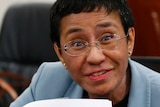 A woman wearing a blue jacket  shows an arrest form after being arrested by the National Bureau of Investigation in Manila.