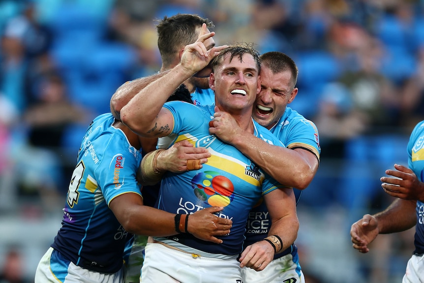 Gold Coast Titans teammates jump on the back of AJ Brimson after a try against North Queensland Cowboys.