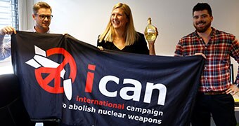 International Campaign to Abolish Nuclear Weapons members hold banner.