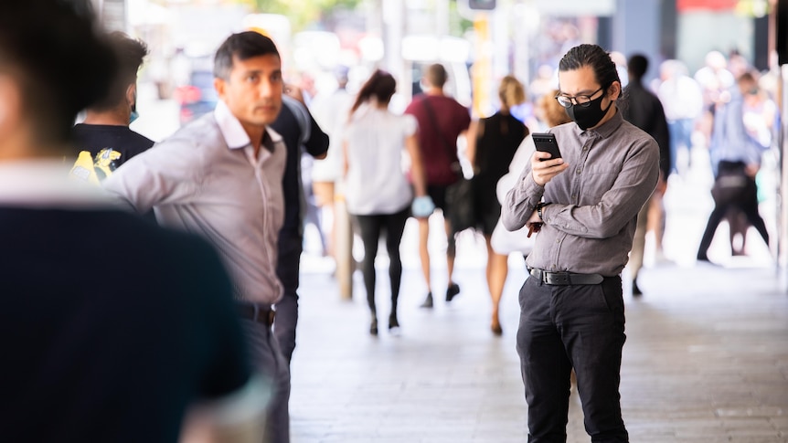A man wearing a mask on his phone.