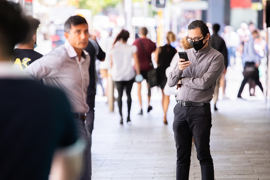 A man wearing a mask on his phone.
