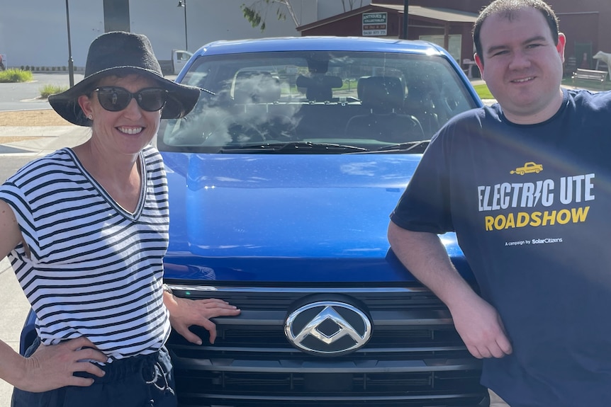 A man and a woman stand with an electric ute.
