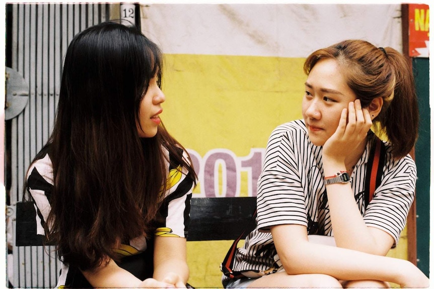 Two women sitting down next to each other and conversing to depict a story about the art and science of conversations.