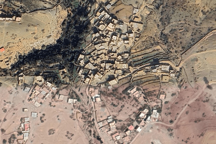 A birds' eye view shows the landscape of a village in a desert mountain region