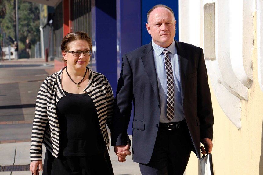 Sophie Mirabella walking down the street to court holding her husband's hand.
