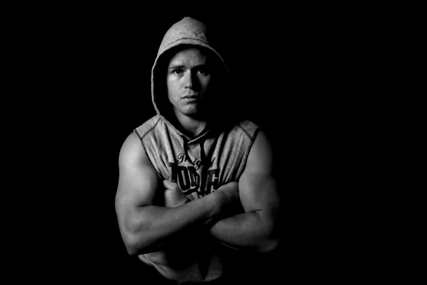 A black and white photo of a man in a hoodie.
