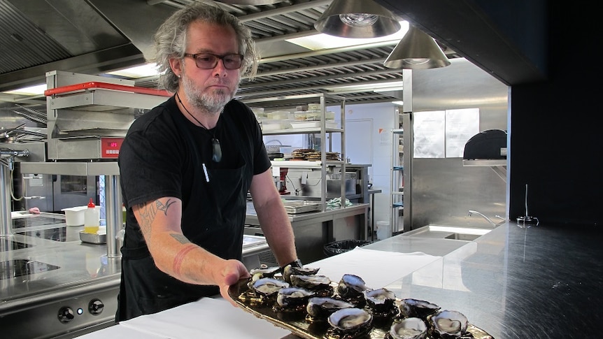 Executive chef Vince Trim delivering a tray of oysters at The Source restaurant.