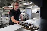 Executive chef Vince Trim delivering a tray of oysters at The Source restaurant.