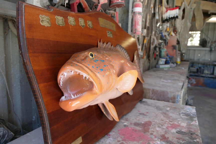 Model of fish on a timber board on a workshop counter top. 