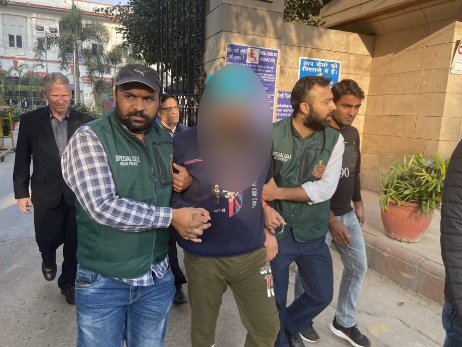 A man with his face blurred out walking in a crowd of Indian police