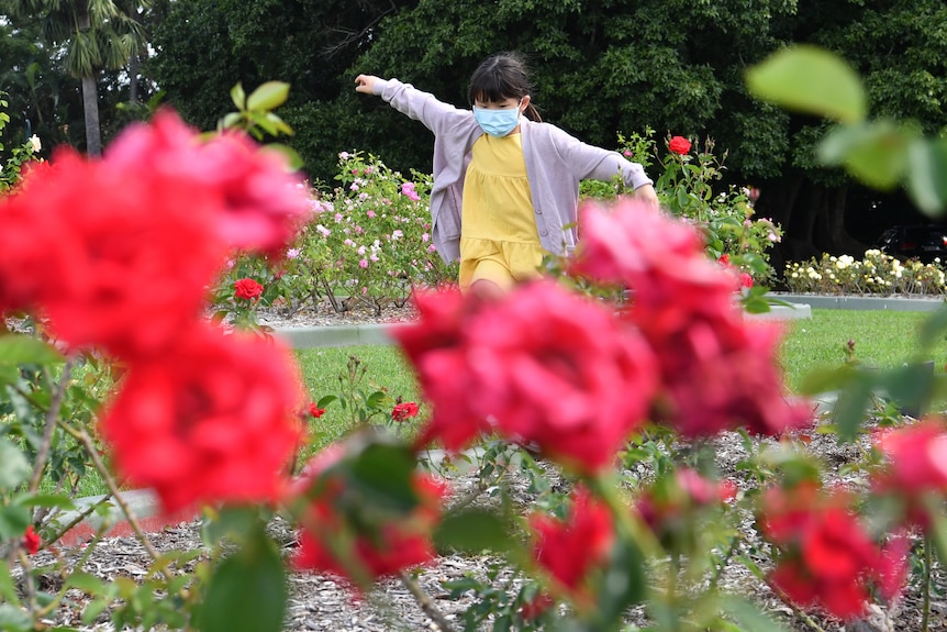 Child in face mask plays in garden