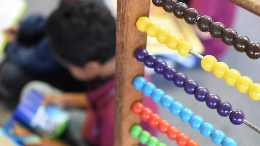 A child reads in a classroom, as seen through a colourful abacus.