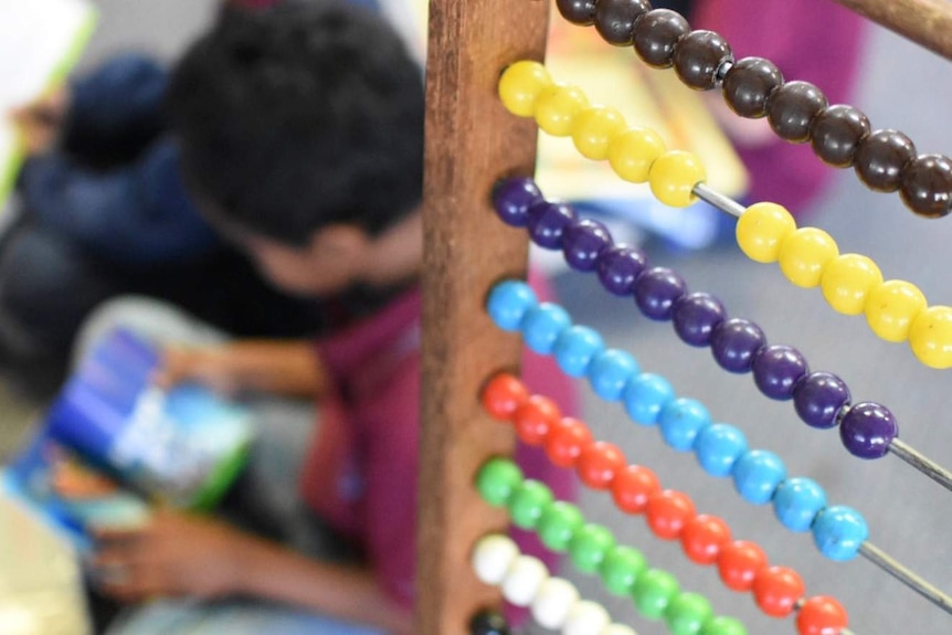 A child reads in a classroom, as seen through a colourful abacus.