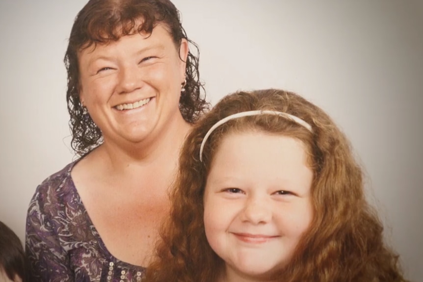 A mother and daughter smile in a family portrait.