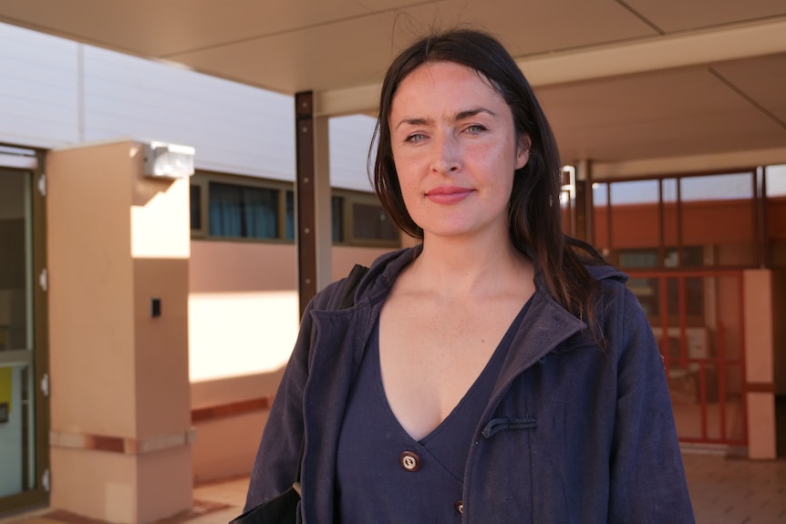 A woman wearing a navy jacket returns the camera's gaze.