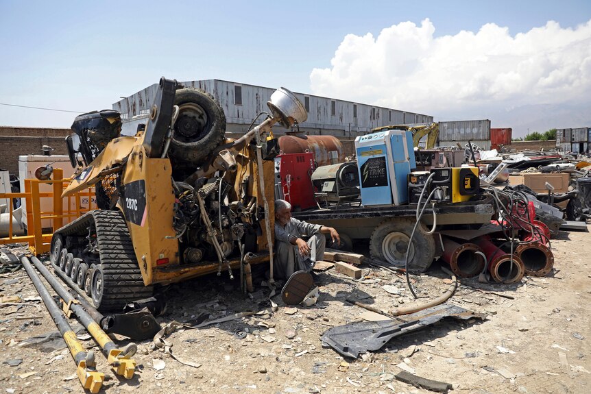 A man rests on a piece of destroyed machinery at a scrapyard in Afghanistan