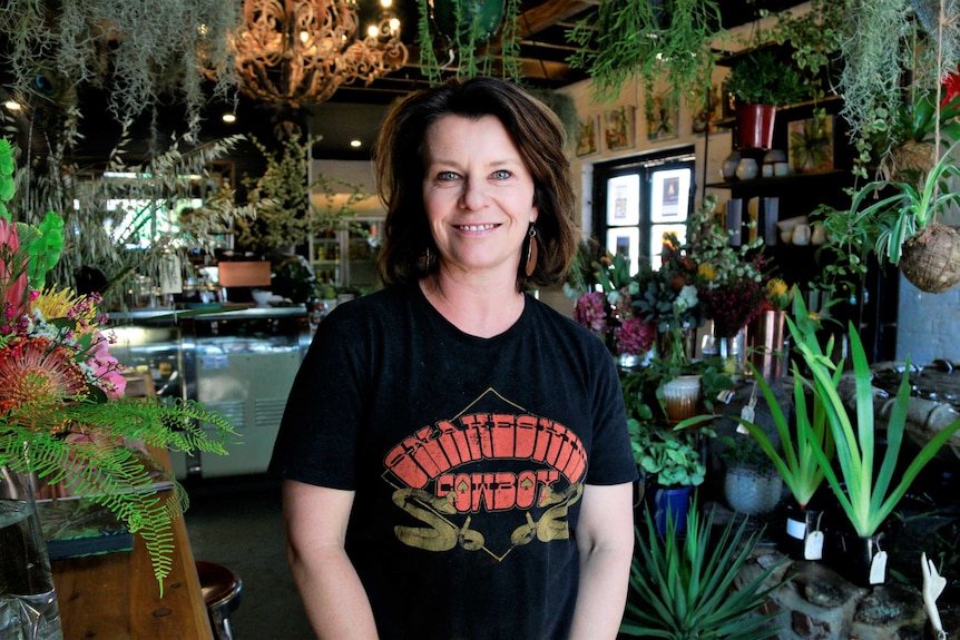 Dee Gasnier stands smiling at the camera while surrounded by the plants the sells in Braidwood.