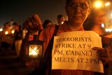 A woman holds a lamp and a poster during a peace rally in memory of those killed in Mumbai