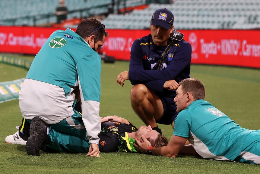 Medical staff attend to Ste3ve smith as he lies on the SCG field after being injured.