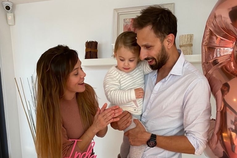 A mum and a dad holding their daughter over a birthday cake