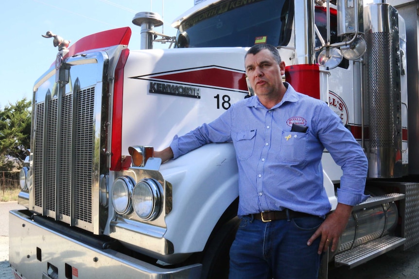 Andy Divall standing outside one of his heavy trucks from trucking ocmpany