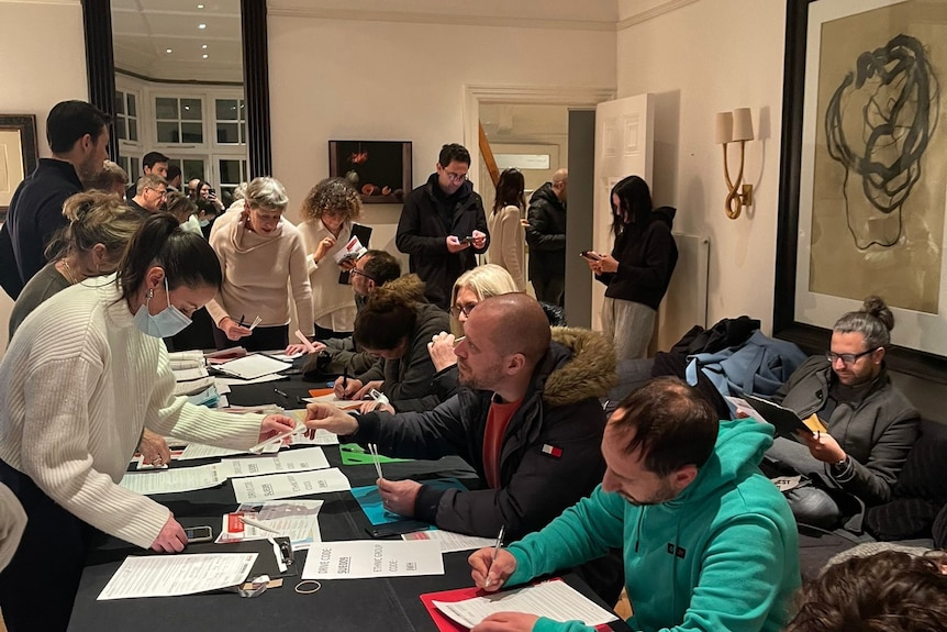 People filling out forms tables in a large room