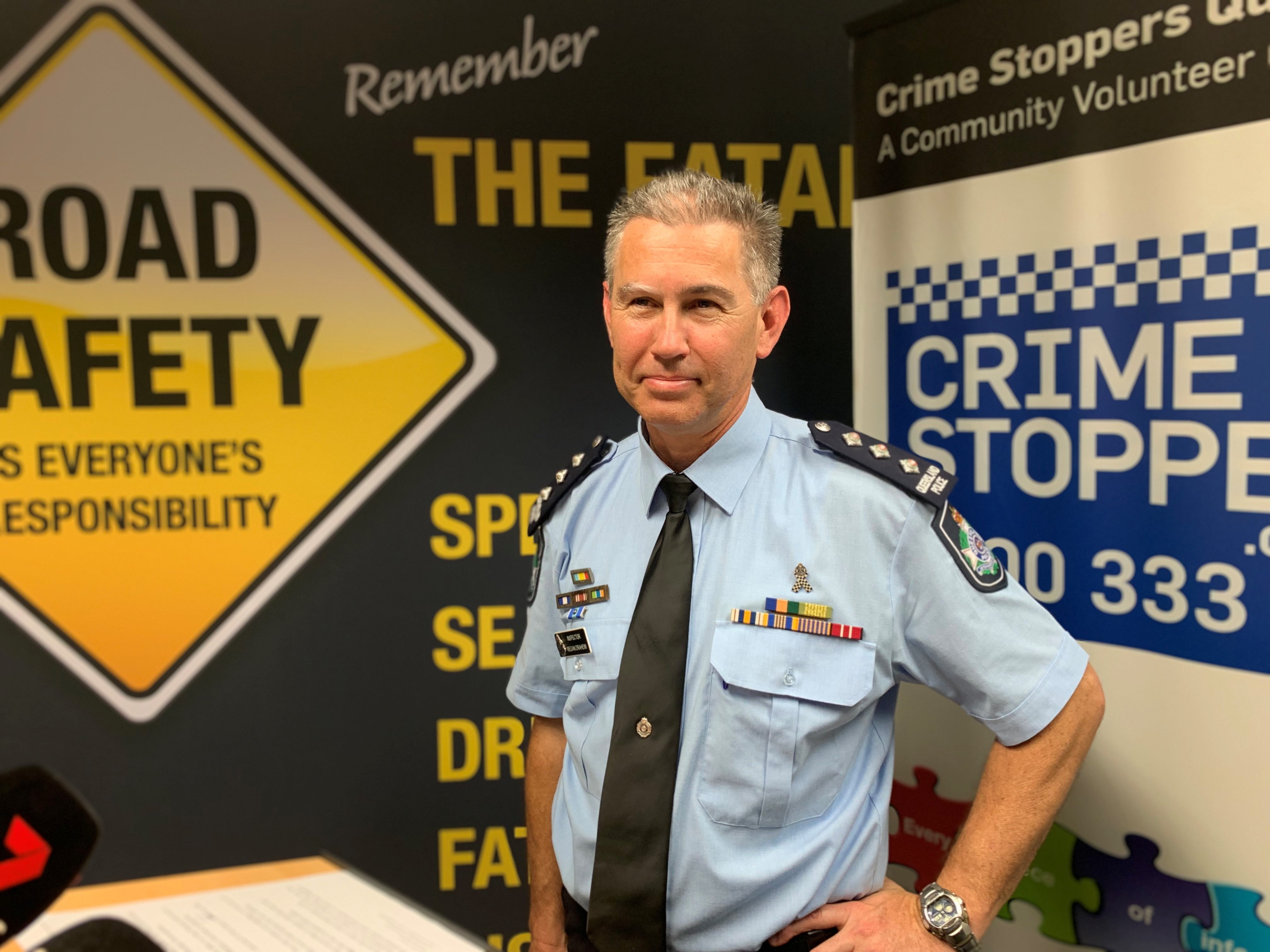 A police officer with short gray hair stands with his hands on his hips.