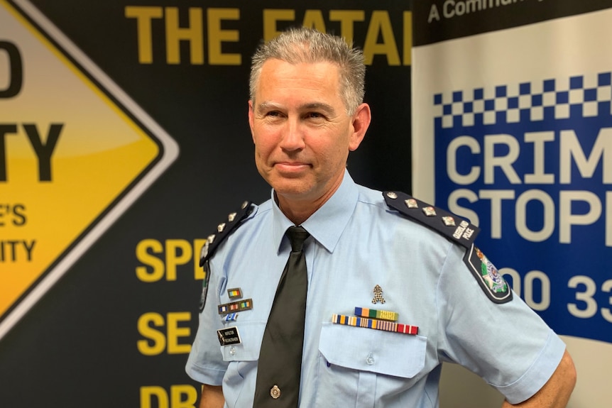 A police officer with short gray hair stands with his hands on his hips.