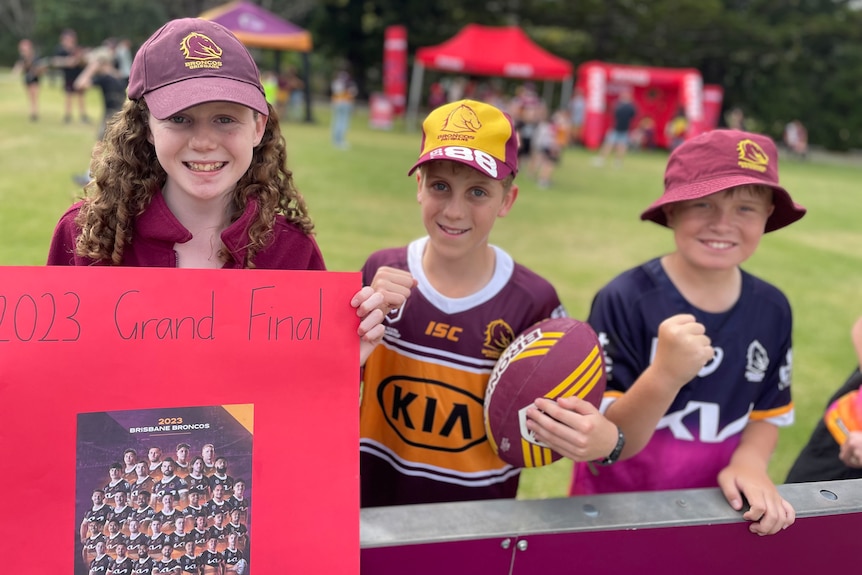 Young fans hold Broncos sign and football