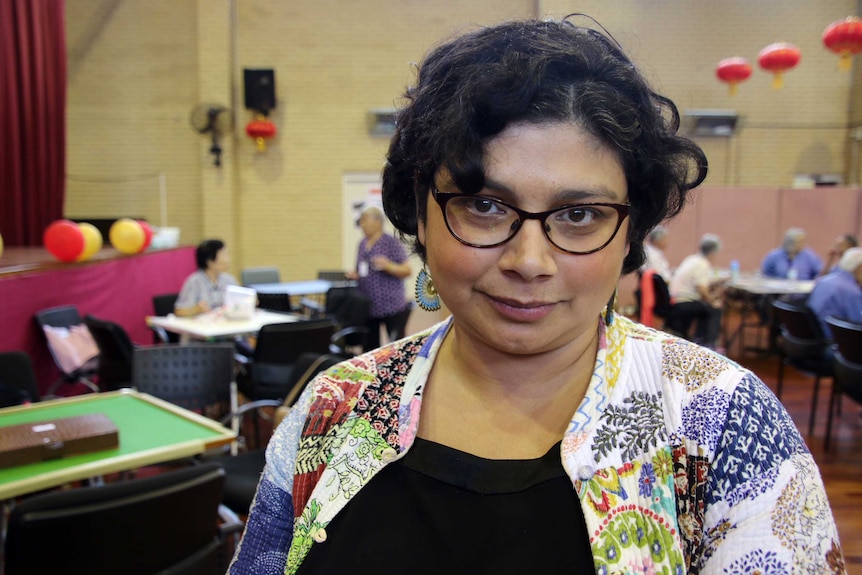 Close-up of Dr Bianca Brijnath, from the National Ageing Research Institute, with chairs and tables in the background.