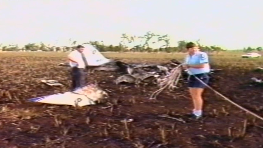 Two men stand around a plane wreckage.