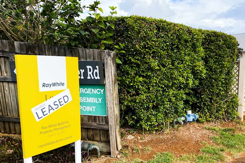 A yellow and white real estate sign with the word "leased" plastered across it. 