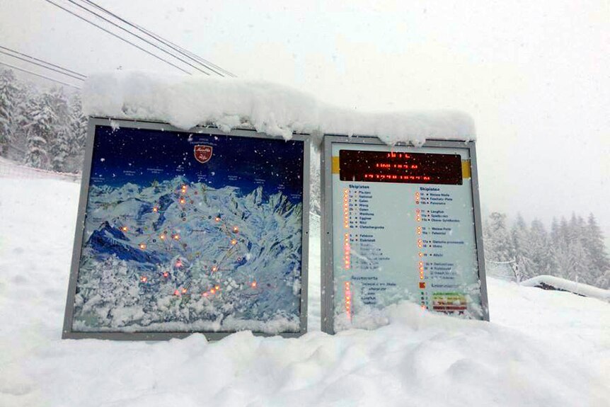 A sign showing which ski runs are open is buried in snow