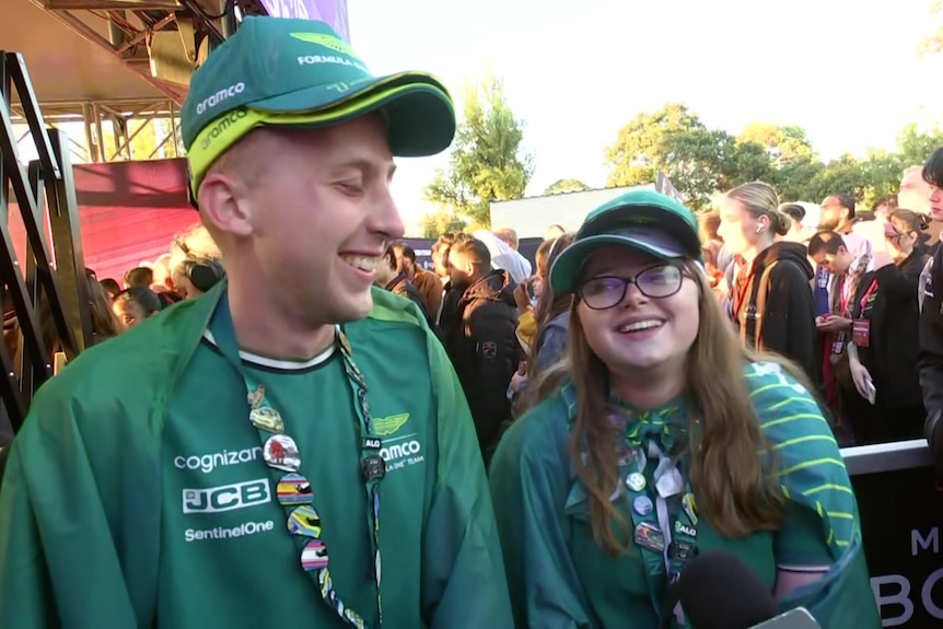 A young man and woman wearing green while smiling at each other