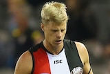 Nick Riewoldt jogs off the field flanked by two trainers during an AFL game.