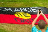 An Aboriginal flag with the words 'change the date'