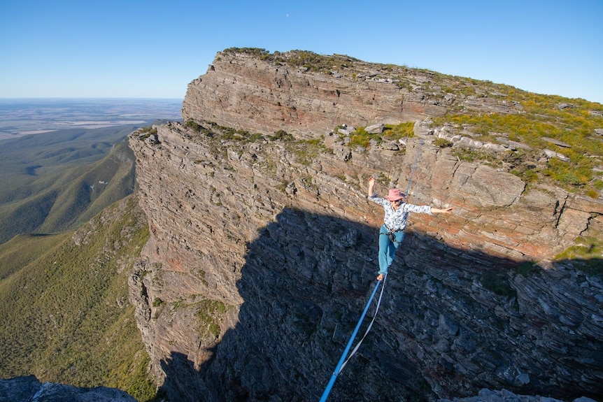 A woman on a tightrope over a deep gorge