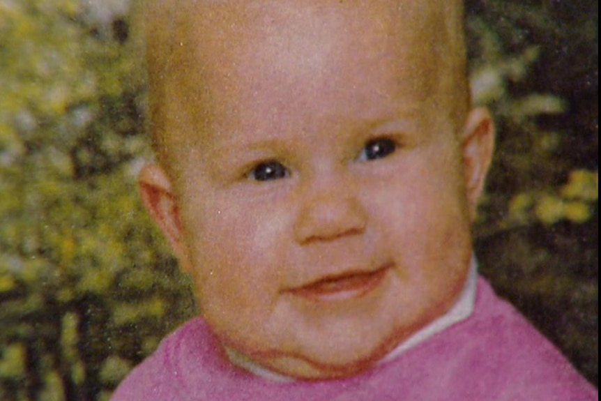 A baby girl wearing a pink top smiling