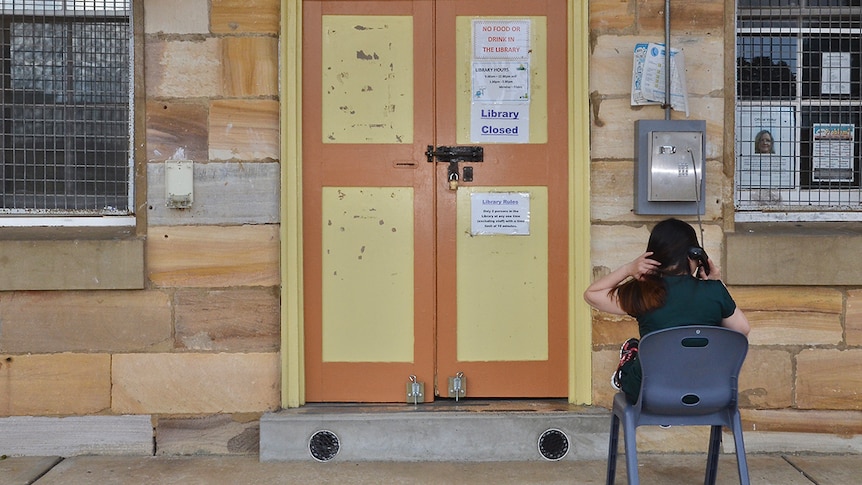 A woman sits outside a library, making a phone call inside the Berrima Correctional Centre