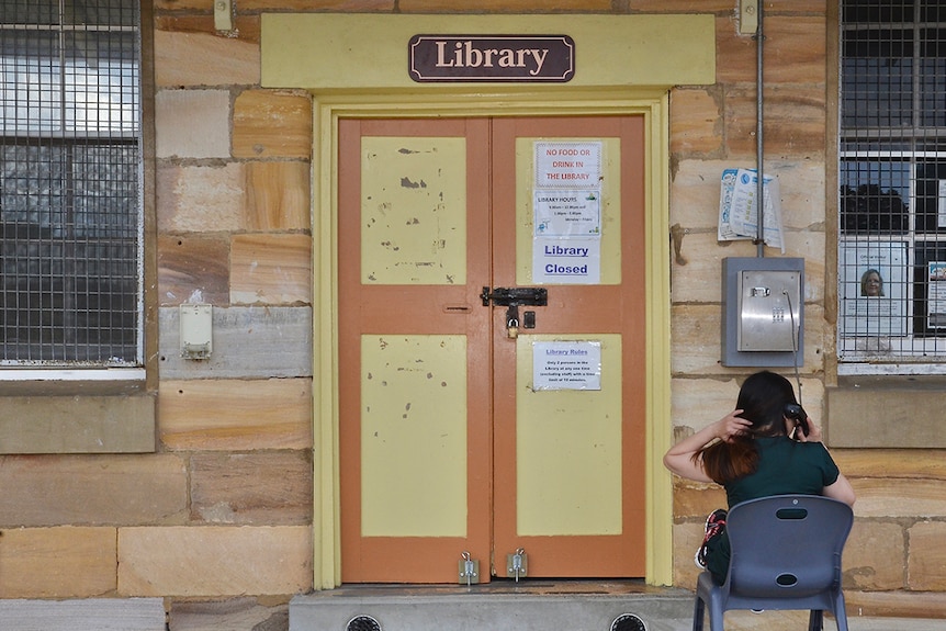 A woman sits outside a library, making a phone call inside the Berrima Correctional Centre