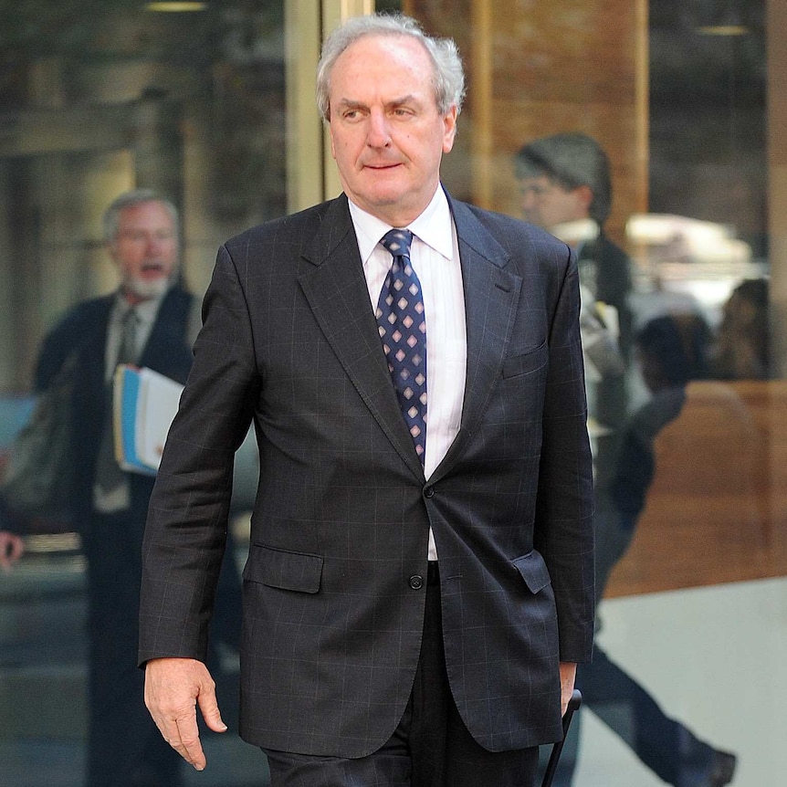 Tim Tobin walking out of a hearing in Melbourne, he is wearing a suit.