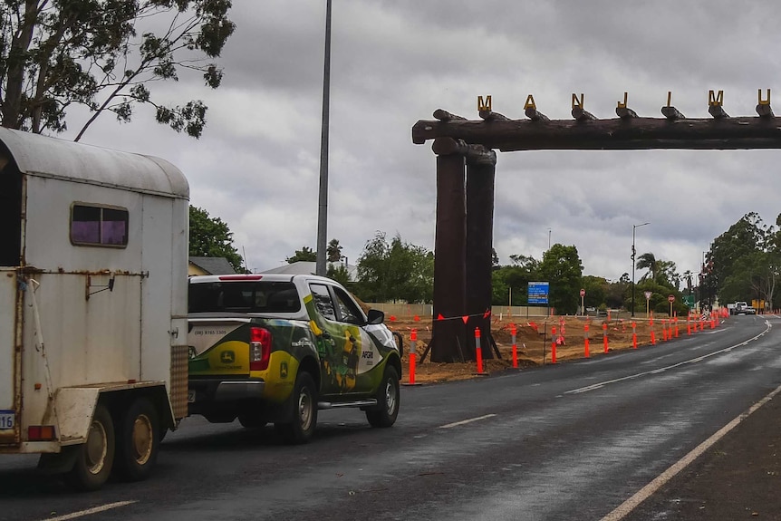 A ute drives on a road heading out of town.