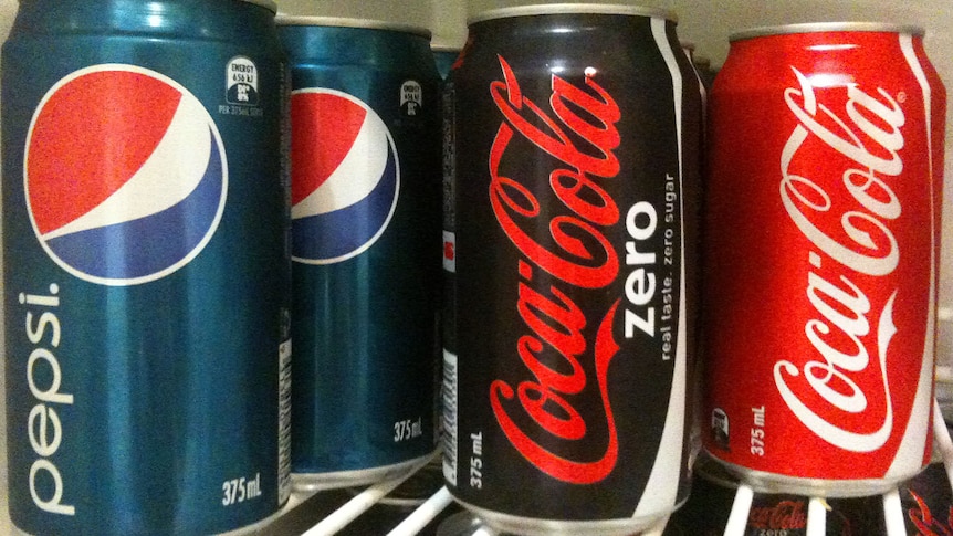 Generic of pepsi, coca-cola zero and original coca-cola sit on a shelf in the fridge.