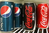 Generic of pepsi, coca-cola zero and original coca-cola sit on a shelf in the fridge.