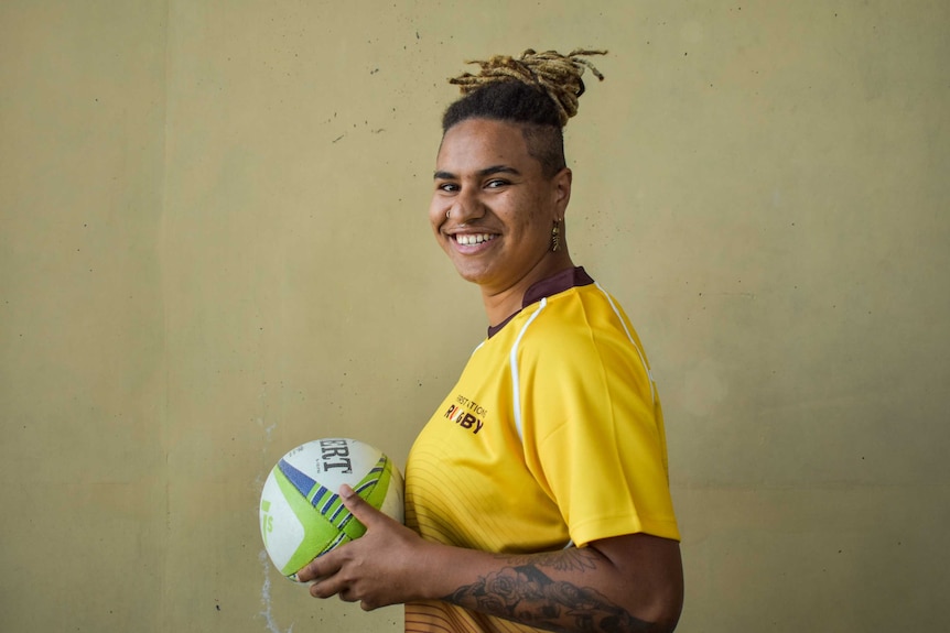 Leilanie Andrews holds a football while smiling for the camera.