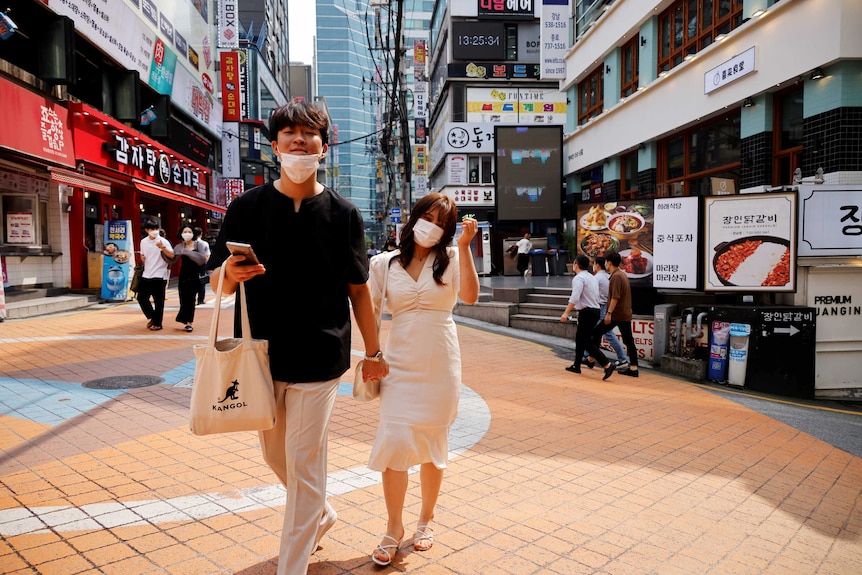 A couple walks in a shopping district of Seoul.